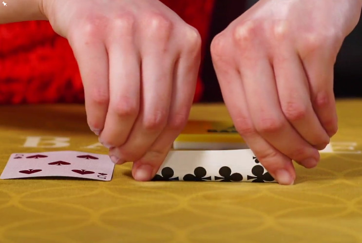 La croupière plie la carte ne laissant apercevoir qu'une petite partie de la valeur de la carte de Baccarat Squeeze Carte pressée du Baccarat Squeeze