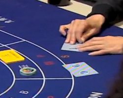 Un joueur plie la carte de baccarat dans un casino de Macao